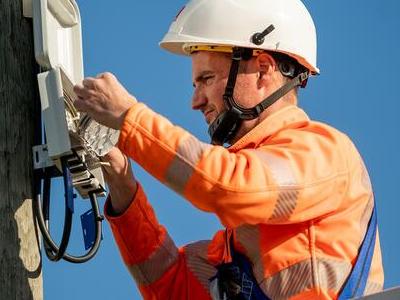 mężczyzna naprawiający skrzynkę na słupie telekomunikacyjnym